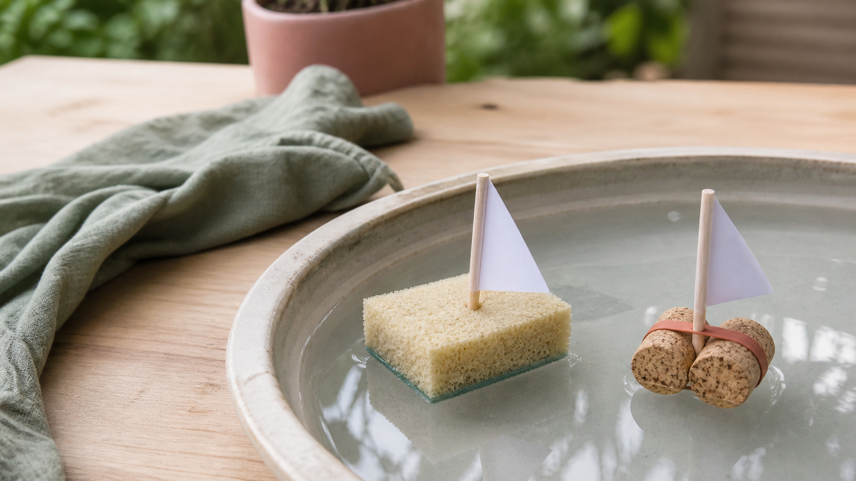 Einfache kleine Boote aus Schwamm und Kork schwimmen in einer flachen Wasserschale.